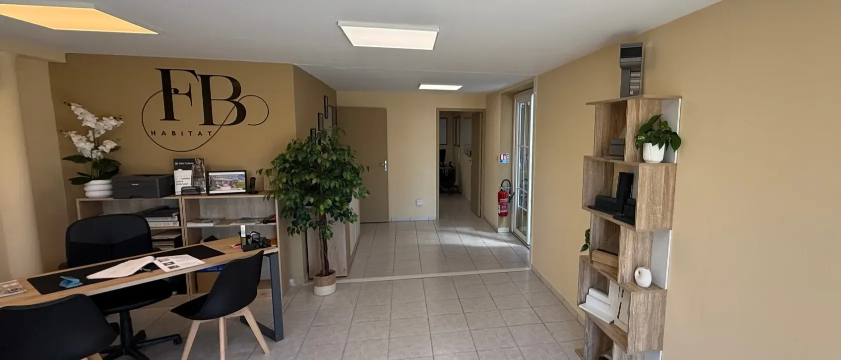 Showroom FB Habitat à Canohès : le logo de l'entreprise peint sur le mur, l'espace conseil et les présentoirs produits