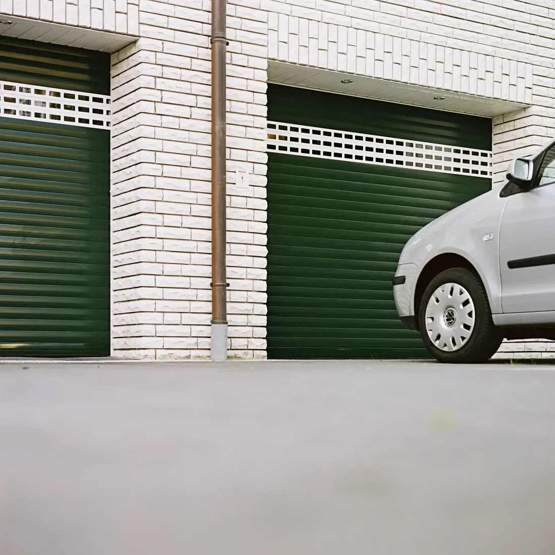 Portes de garage enroulables aluminium sur une façade en brique blanche